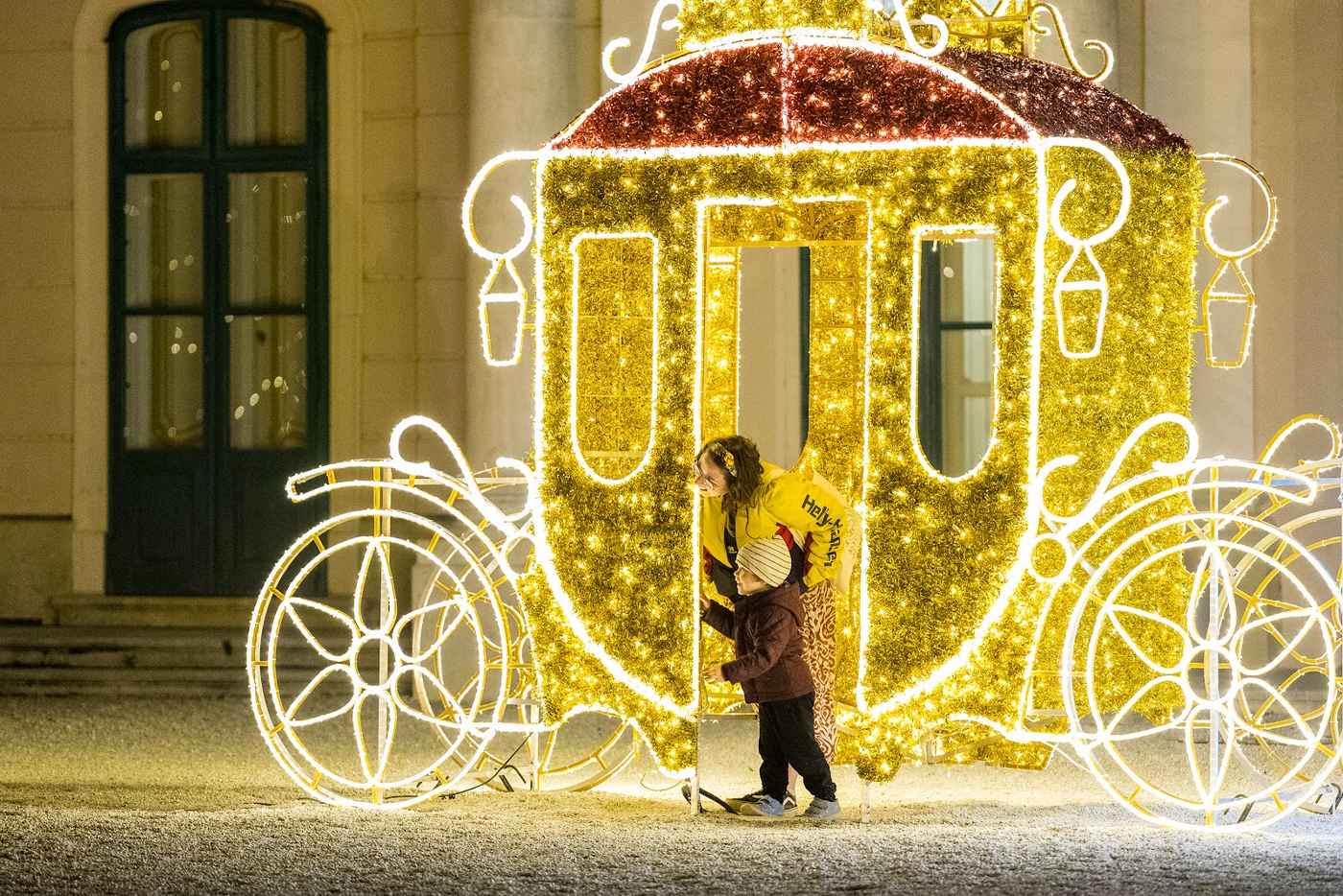 Goldene Leuchtkutsche mit Figuren einer Frau und eines Kindes am Eingang.